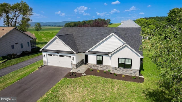 view of front of property with a front lawn, a mountain view, and a garage