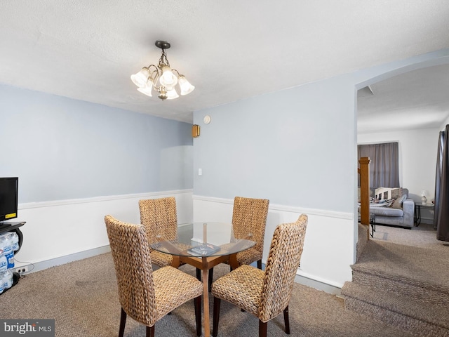 dining space with a textured ceiling, a notable chandelier, and carpet flooring