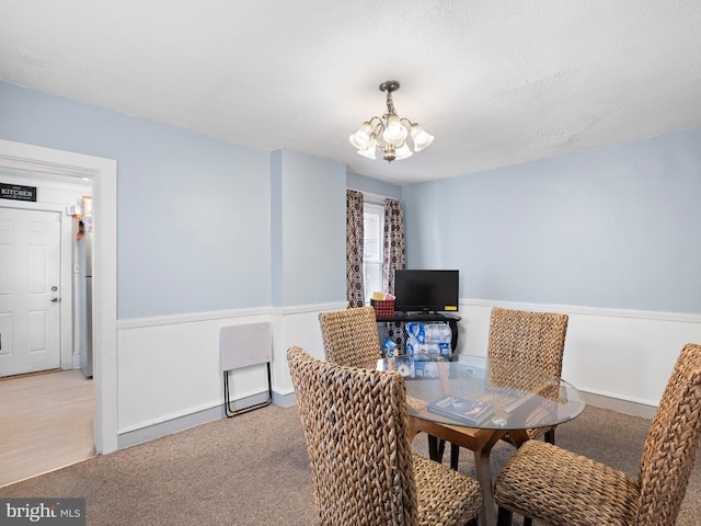 carpeted dining area with a chandelier