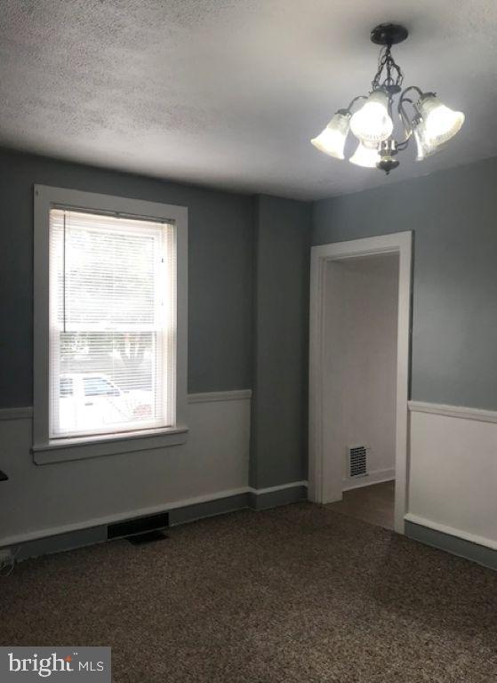 unfurnished room with a notable chandelier and a textured ceiling