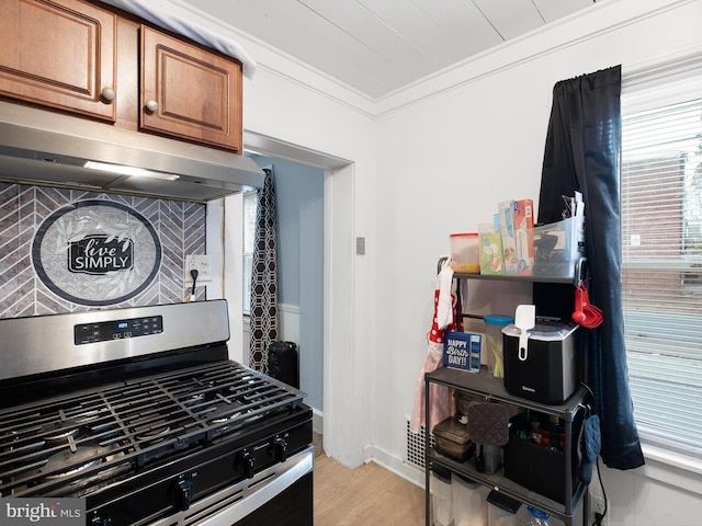 kitchen with range hood, crown molding, light hardwood / wood-style flooring, and stainless steel range with gas stovetop