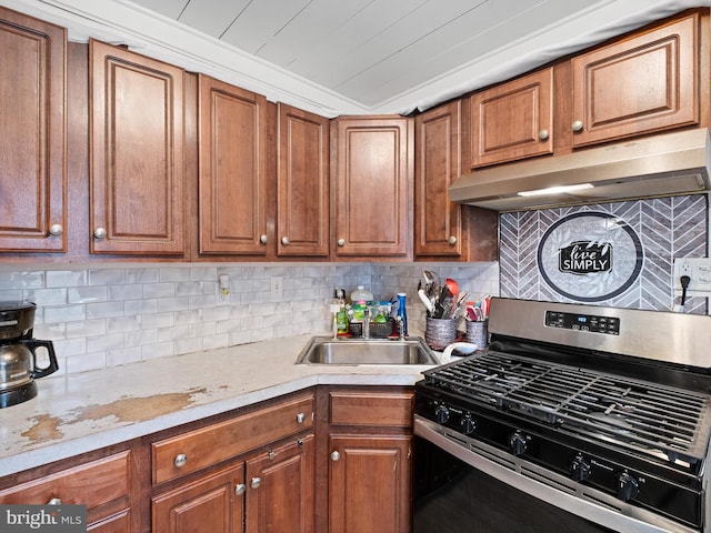 kitchen with stainless steel gas range, crown molding, backsplash, and sink