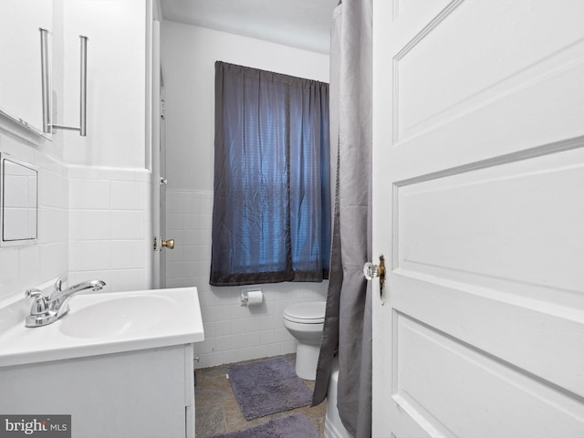 bathroom with tile walls, toilet, and vanity