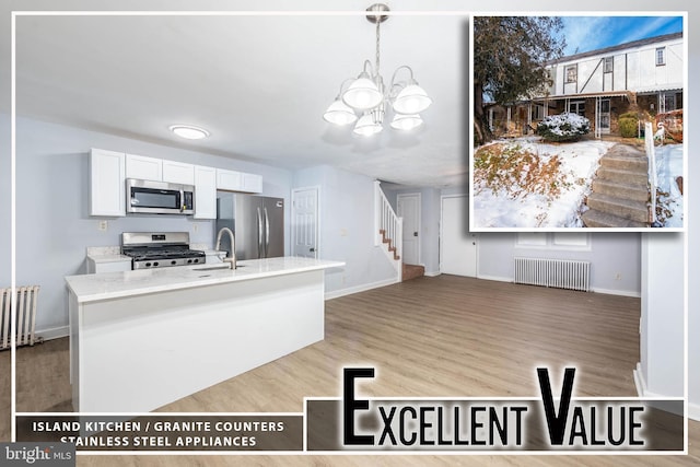 kitchen with radiator heating unit, appliances with stainless steel finishes, white cabinetry, hanging light fixtures, and sink