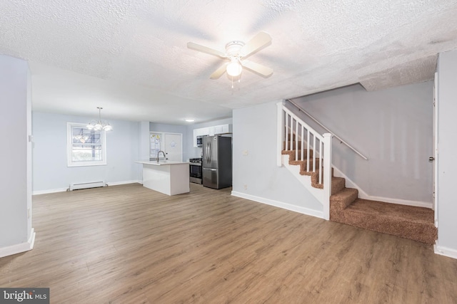 unfurnished living room featuring wood-type flooring, a baseboard radiator, a textured ceiling, and sink