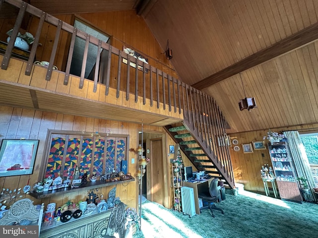 carpeted living room with wood ceiling, beam ceiling, and wood walls