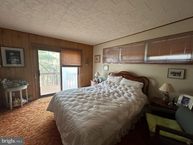 bedroom featuring access to exterior, wooden walls, and carpet