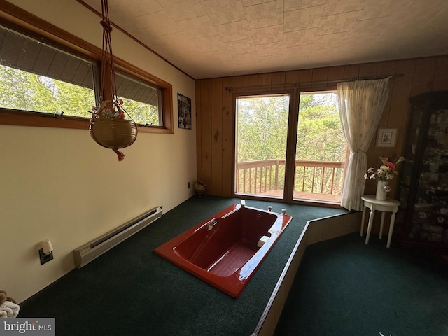 game room with dark colored carpet, wooden walls, and a baseboard heating unit