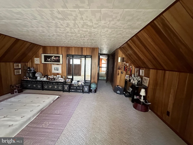 carpeted bedroom featuring lofted ceiling and wood walls