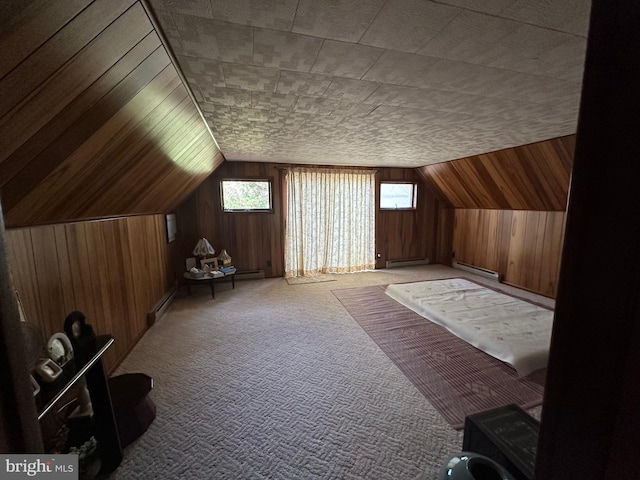 additional living space with light colored carpet, a baseboard radiator, vaulted ceiling, and wood walls