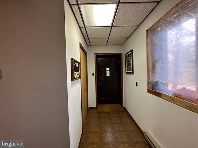 hall with a paneled ceiling and baseboard heating