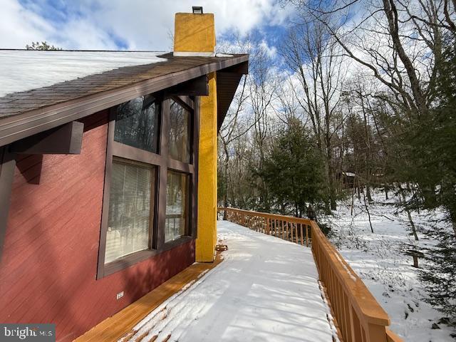 view of snowy exterior with a wooden deck