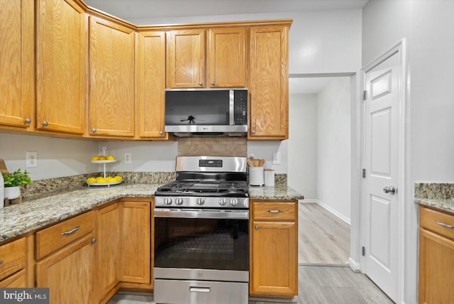 kitchen featuring light wood-type flooring, light stone counters, and stainless steel appliances