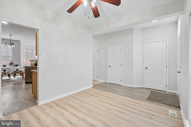 spare room featuring ceiling fan with notable chandelier and light hardwood / wood-style flooring