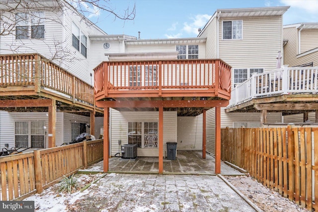 snow covered rear of property featuring a wooden deck and central AC