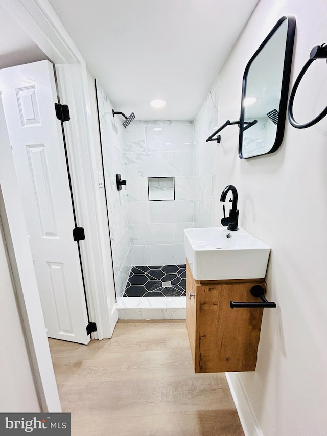 bathroom featuring hardwood / wood-style flooring, vanity, and a tile shower