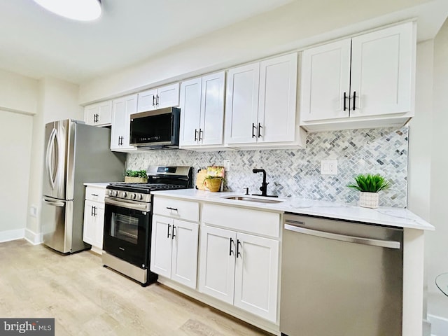 kitchen with backsplash, appliances with stainless steel finishes, sink, and white cabinets