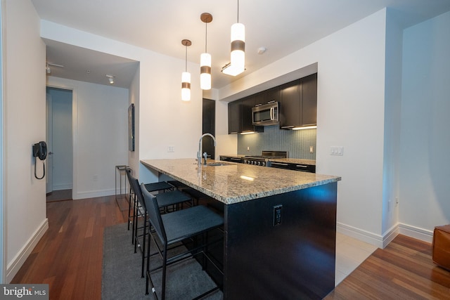 kitchen featuring pendant lighting, a kitchen bar, decorative backsplash, kitchen peninsula, and light stone counters