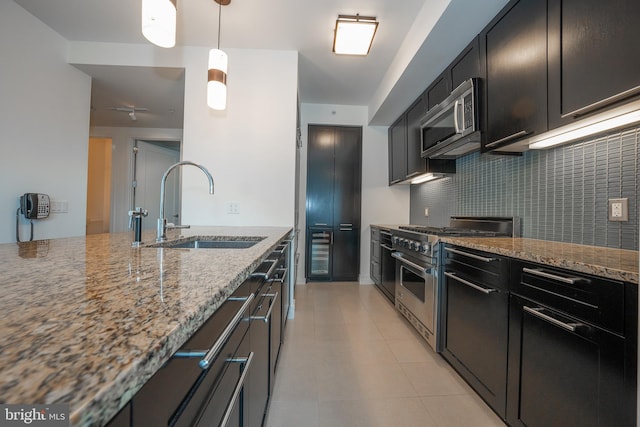 kitchen with appliances with stainless steel finishes, light stone counters, tasteful backsplash, and sink