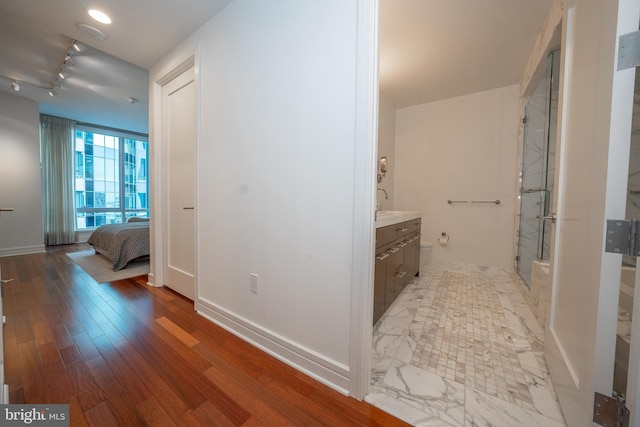 corridor featuring rail lighting and light hardwood / wood-style floors