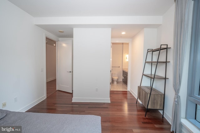 unfurnished bedroom featuring dark wood-type flooring and connected bathroom