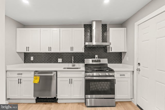 kitchen featuring white cabinets, wall chimney exhaust hood, sink, and stainless steel appliances