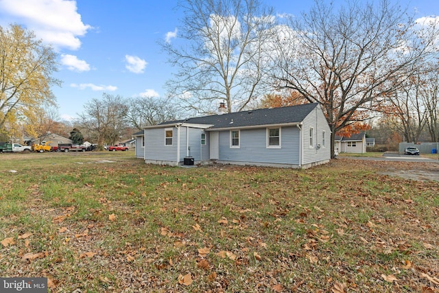 rear view of house featuring cooling unit and a lawn