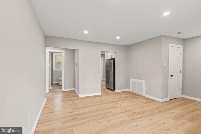 unfurnished bedroom featuring ensuite bathroom, light hardwood / wood-style flooring, and stainless steel fridge