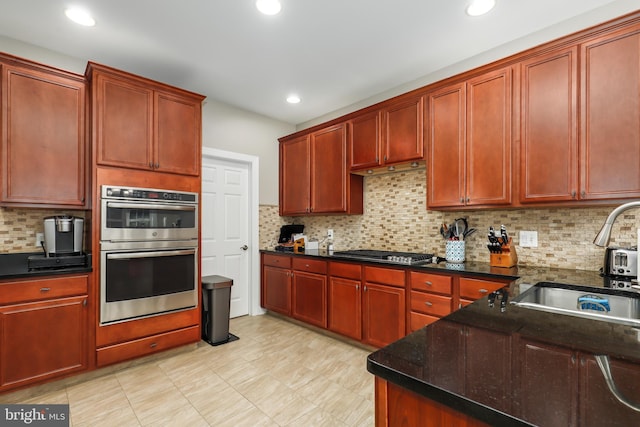 kitchen with sink, stainless steel appliances, dark stone counters, and tasteful backsplash