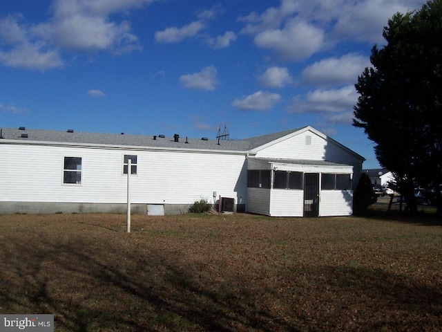 rear view of property featuring a lawn, cooling unit, and a sunroom