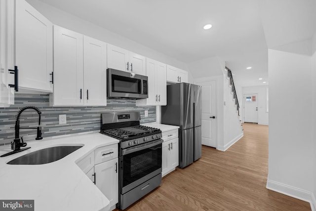 kitchen featuring light wood-type flooring, stainless steel appliances, white cabinetry, and sink