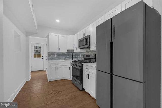 kitchen with backsplash, hardwood / wood-style floors, sink, appliances with stainless steel finishes, and white cabinets