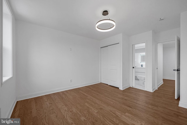 unfurnished bedroom featuring hardwood / wood-style floors, a closet, and connected bathroom