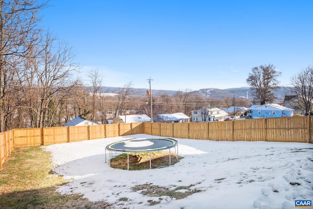 yard covered in snow with a mountain view and a trampoline