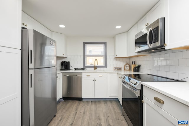 kitchen featuring light hardwood / wood-style floors, sink, white cabinetry, and appliances with stainless steel finishes