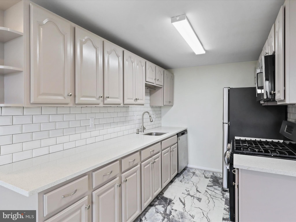 kitchen featuring light stone counters, sink, backsplash, and stainless steel appliances