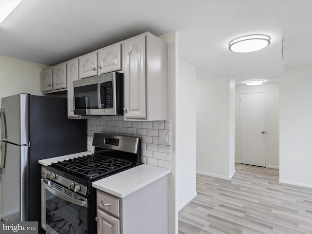 kitchen featuring appliances with stainless steel finishes, light hardwood / wood-style floors, and backsplash