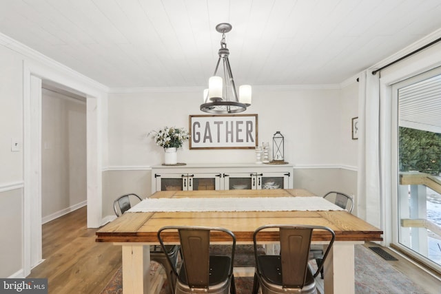 dining space featuring ornamental molding, wood-type flooring, and a notable chandelier