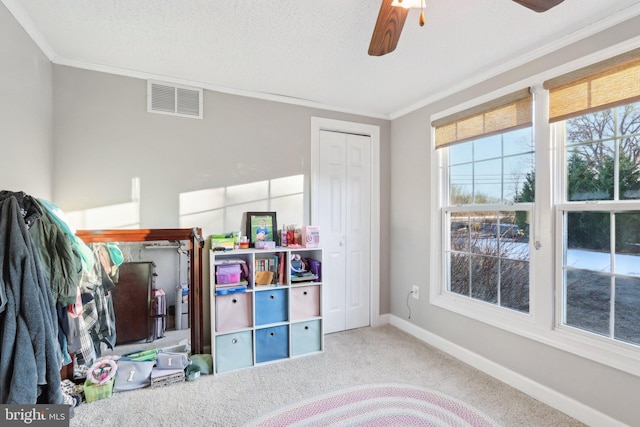 rec room featuring ceiling fan, a textured ceiling, ornamental molding, and carpet flooring