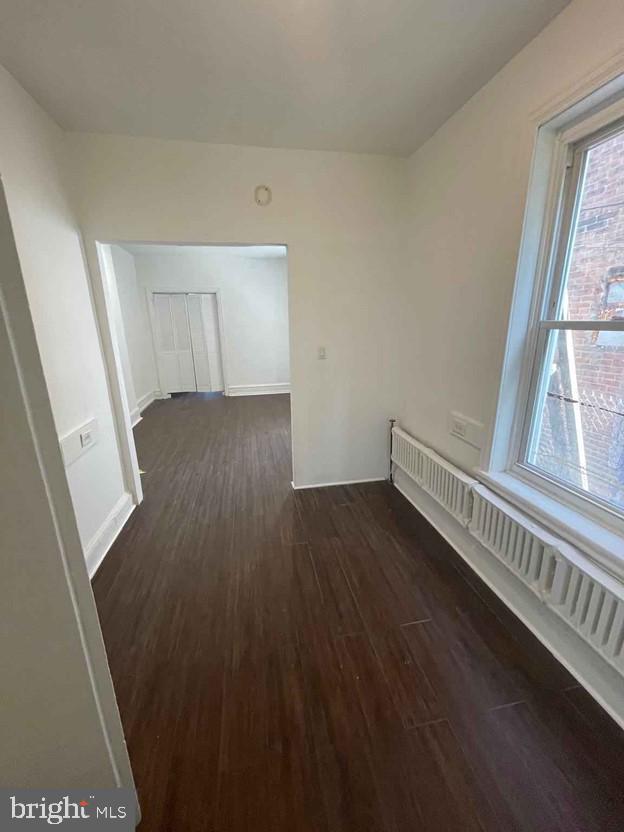 spare room featuring a baseboard radiator and dark hardwood / wood-style flooring