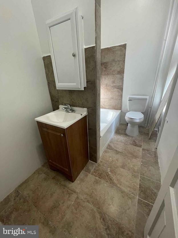 bathroom with vanity, a tub, and toilet