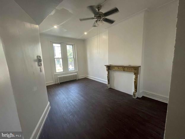 unfurnished living room featuring dark wood-type flooring, radiator heating unit, ceiling fan, and vaulted ceiling