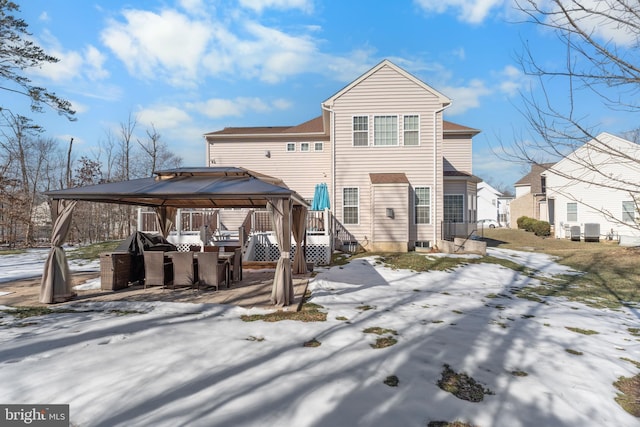 snow covered rear of property featuring a gazebo and central air condition unit