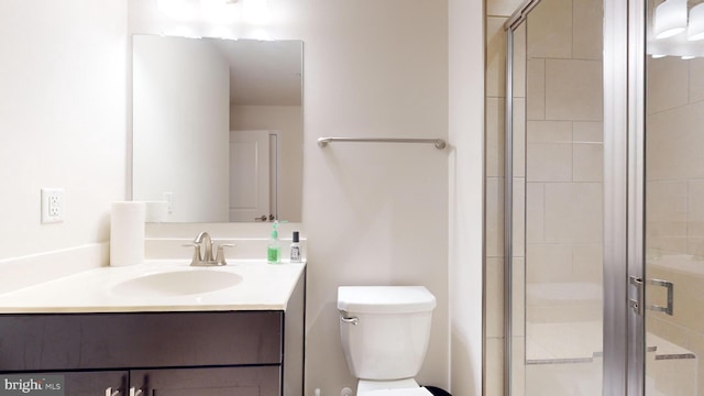 bathroom with vanity, a shower with shower door, and toilet