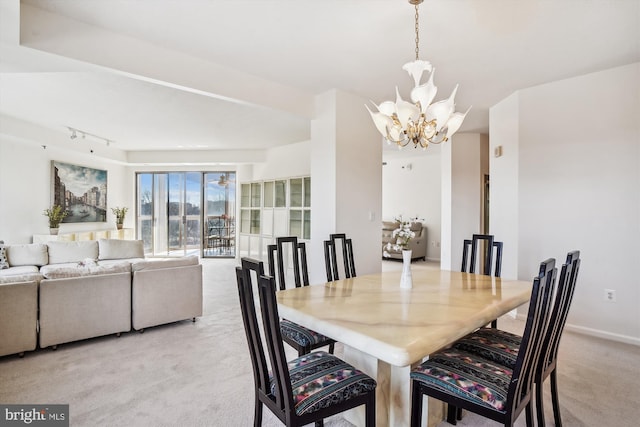 dining area with rail lighting, baseboards, a chandelier, and light colored carpet