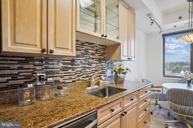 kitchen with stone counters, backsplash, light brown cabinets, a sink, and light tile patterned flooring