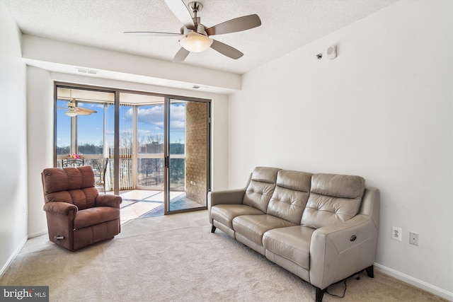 living room featuring a textured ceiling, ceiling fan, carpet, and baseboards