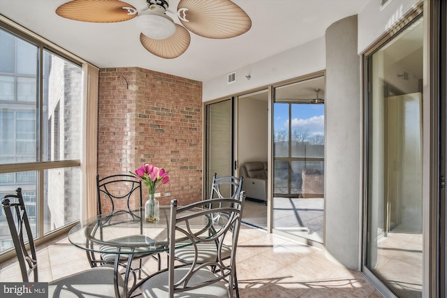 dining area featuring ceiling fan, light tile patterned floors, brick wall, visible vents, and floor to ceiling windows