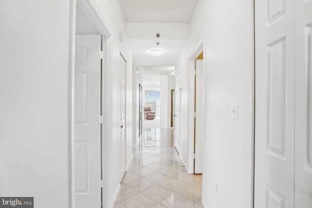 hall with light tile patterned flooring and baseboards