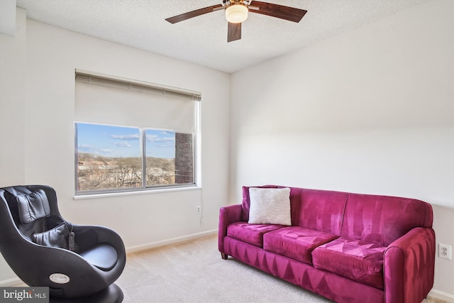 living area with carpet floors, a textured ceiling, baseboards, and a ceiling fan